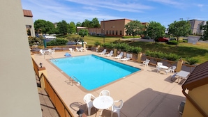 A rooftop pool area with a rectangular pool, white lounge chairs, and a small table. - Days Inn by Wyndham Goodlettsville/Nashville (Goodlettsville)