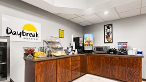 A breakfast area with a sign reading "Daybreak Breakfast," a juice dispenser, a microwave, and a coffee machine. - Days Inn by Wyndham Goodlettsville/Nashville (Goodlettsville)
