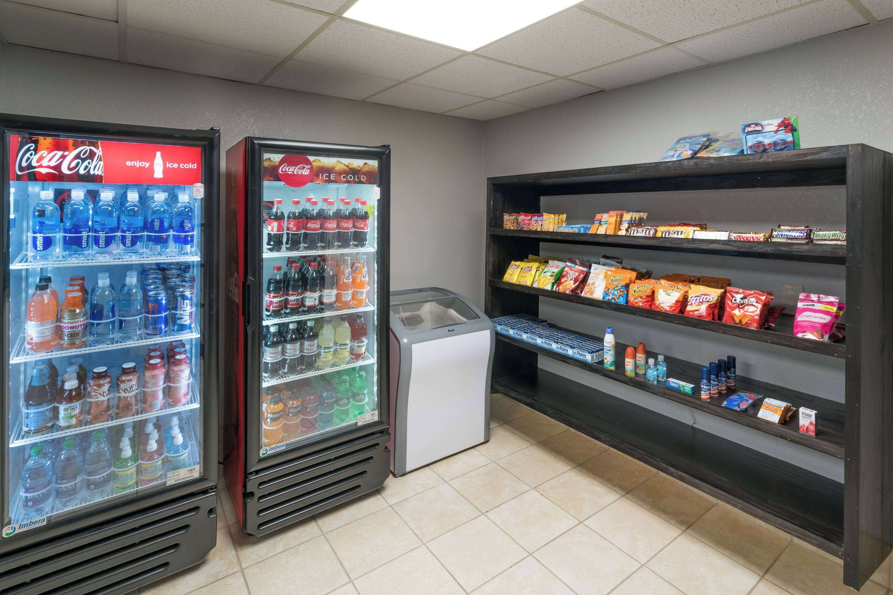 Een automatenruimte met Coca-Cola koelkasten en schappen voor snacks.