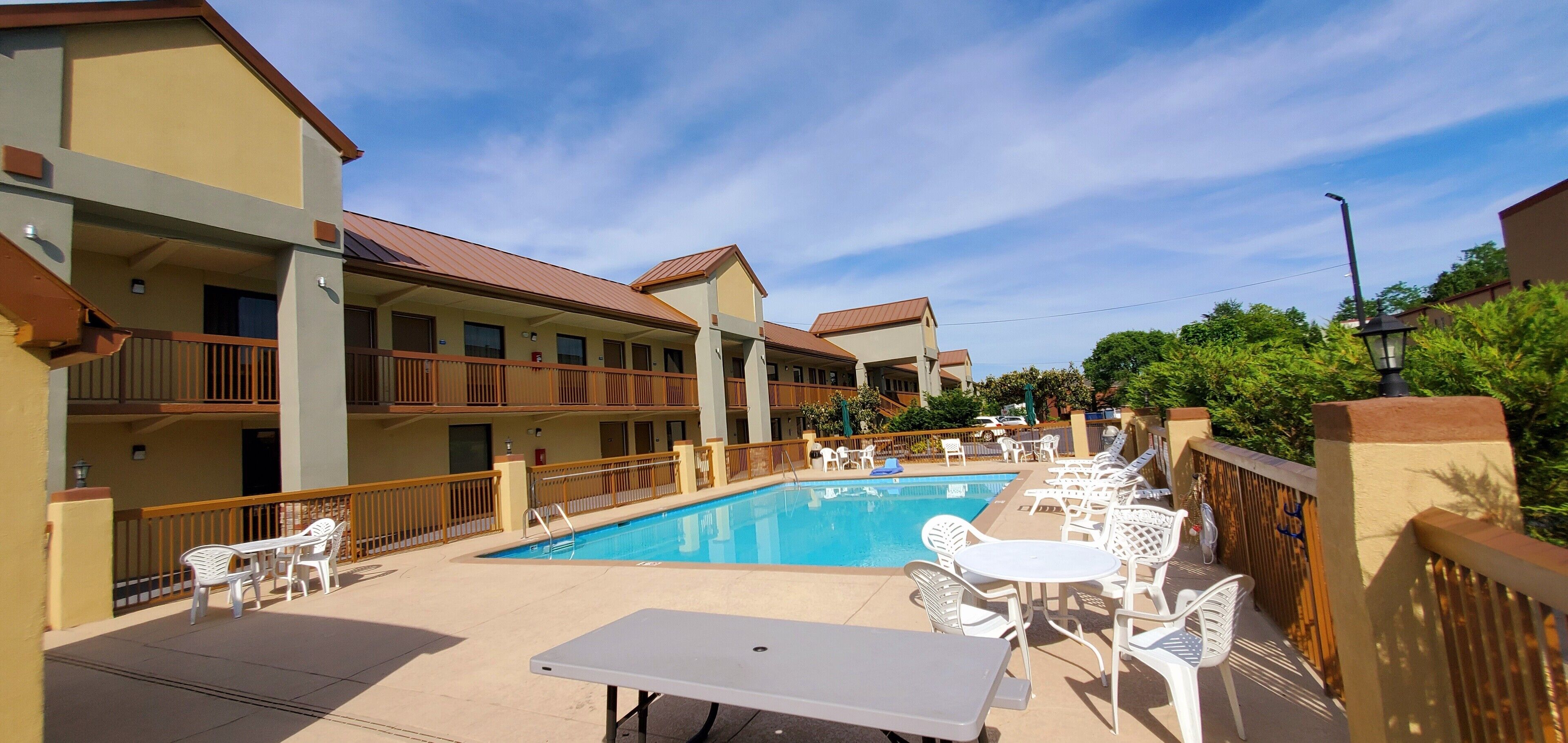 A hotel with a swimming pool, outdoor seating, and balconies.