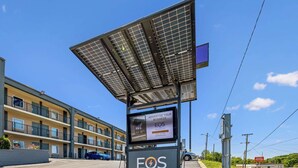 Una estación de carga alimentada por energía solar con un anuncio digital para EOS Charge.
