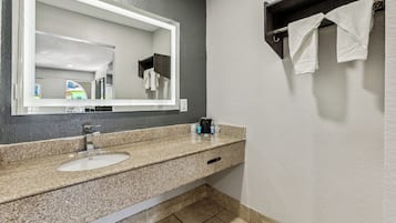A bathroom with a granite countertop, two sinks, a large mirror, and a towel rack.