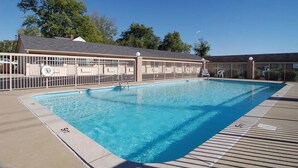 Ein Schwimmbecken mit Holzterrasse, überdachter Sitzgelegenheit und Rettungsturm.
