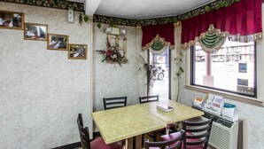Ein Eckzimmer mit Tisch, Stühlen, einem Fenster mit Ausblick und Wanddekorationen.