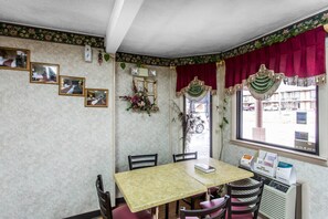 Habitación de esquina con una mesa, sillas, ventana con vistas y adornos en la pared.