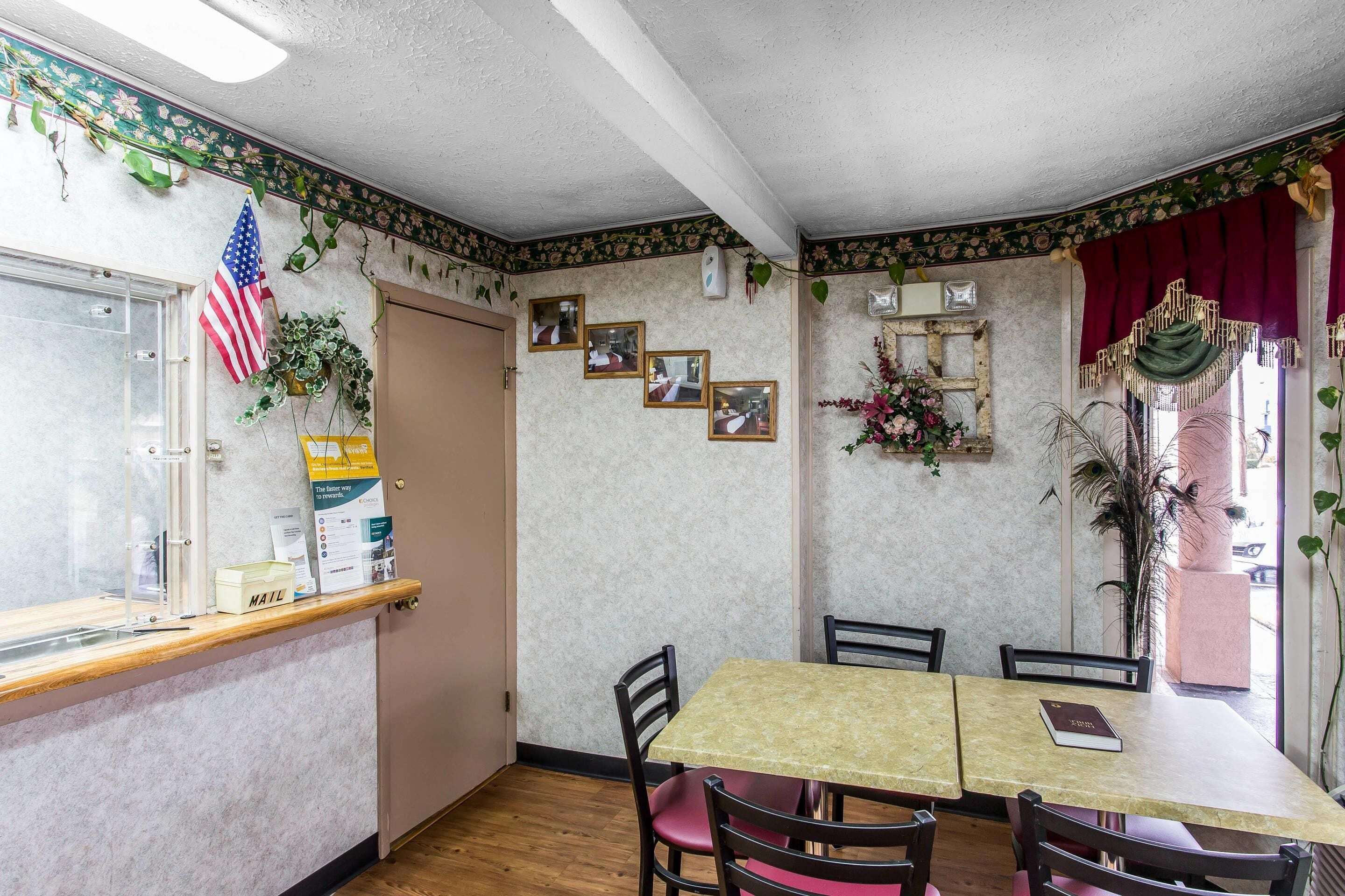 Un coin repas avec une table et des chaises en bois, une fente pour le courrier et une porte ornée d’un drapeau américain.