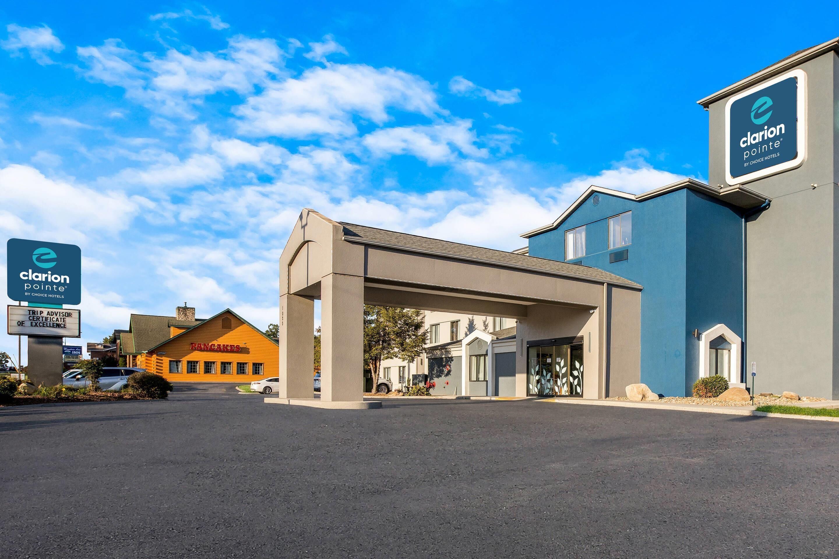 Ingresso di un hotel con portico coperto, insegna Clarion Pointe by Choice Hotels e un edificio con facciata blu.