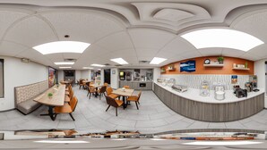 A panoramic view of a modern restaurant with a curved counter, multiple seating areas, and a visible kitchen area. - Clarion Pointe Sevierville-Pigeon Forge (Sevierville)