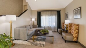 A modern living room with a sectional sofa, a coffee table, a lamp, and a staircase. - Clarion Pointe Sevierville-Pigeon Forge (Sevierville)