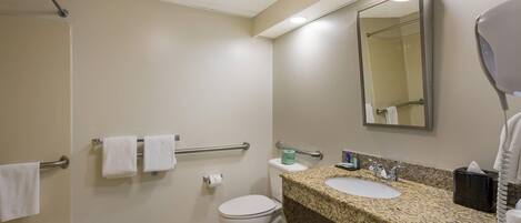 A hotel bathroom with a shower, toilet, sink, and a mirror.