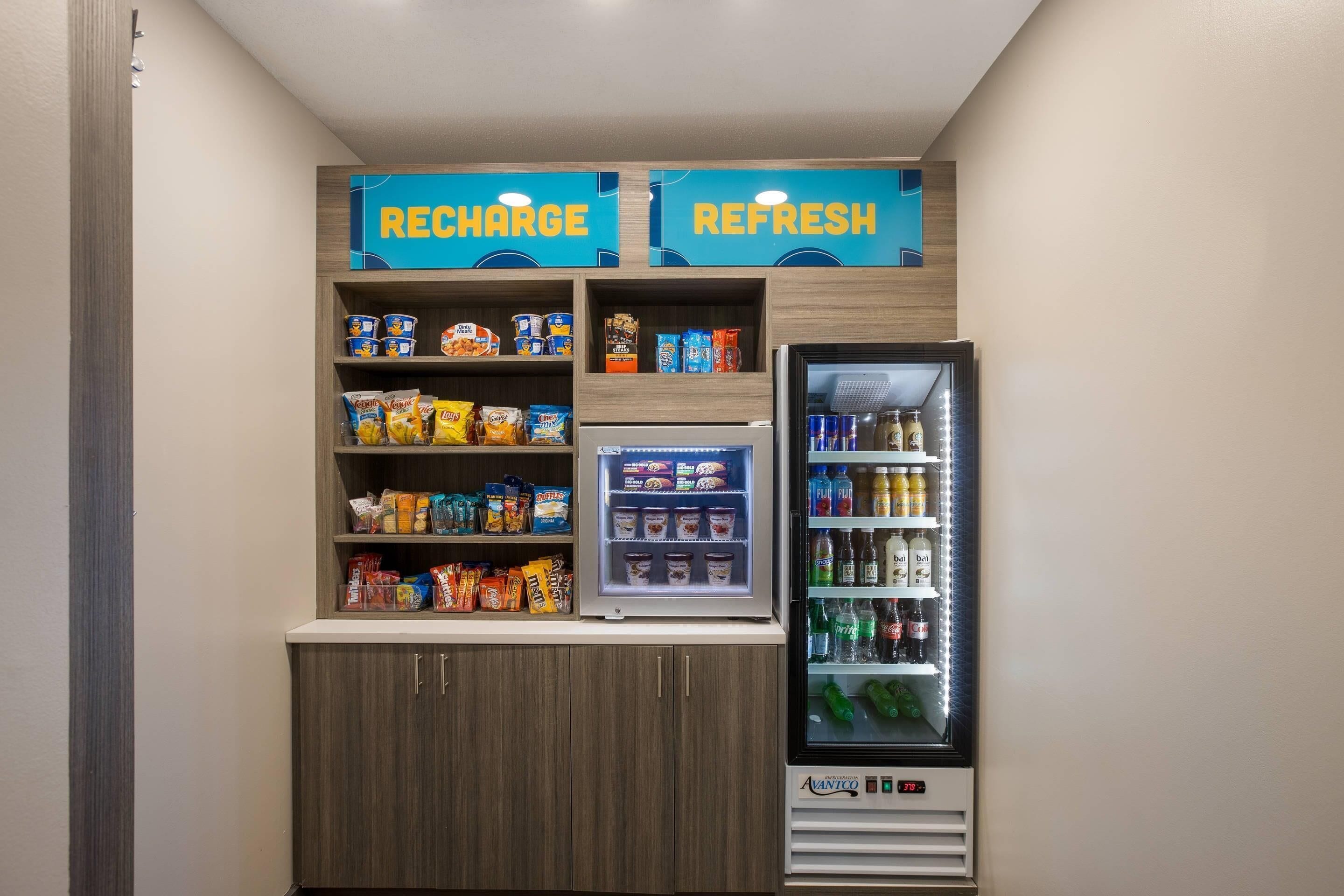 Un área de venta con aperitivos y bebidas, con la etiqueta 'RECHARGE' y 'REFRESH'.