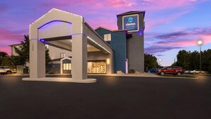 A Clarion Pointe hotel with a modern entrance, illuminated signage, and a parking area with several cars. - Clarion Pointe Sevierville-Pigeon Forge (Sevierville)