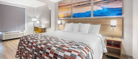 Una habitación de hotel con una cama grande, un cabecero de madera, una mesita de noche, una lámpara y una obra de arte colgada en la pared.