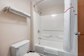 A bathroom with a toilet, a bathtub, and a shower curtain.