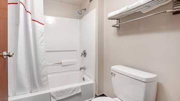 Een badkamer met een bad, toilet en een douchegordijn.