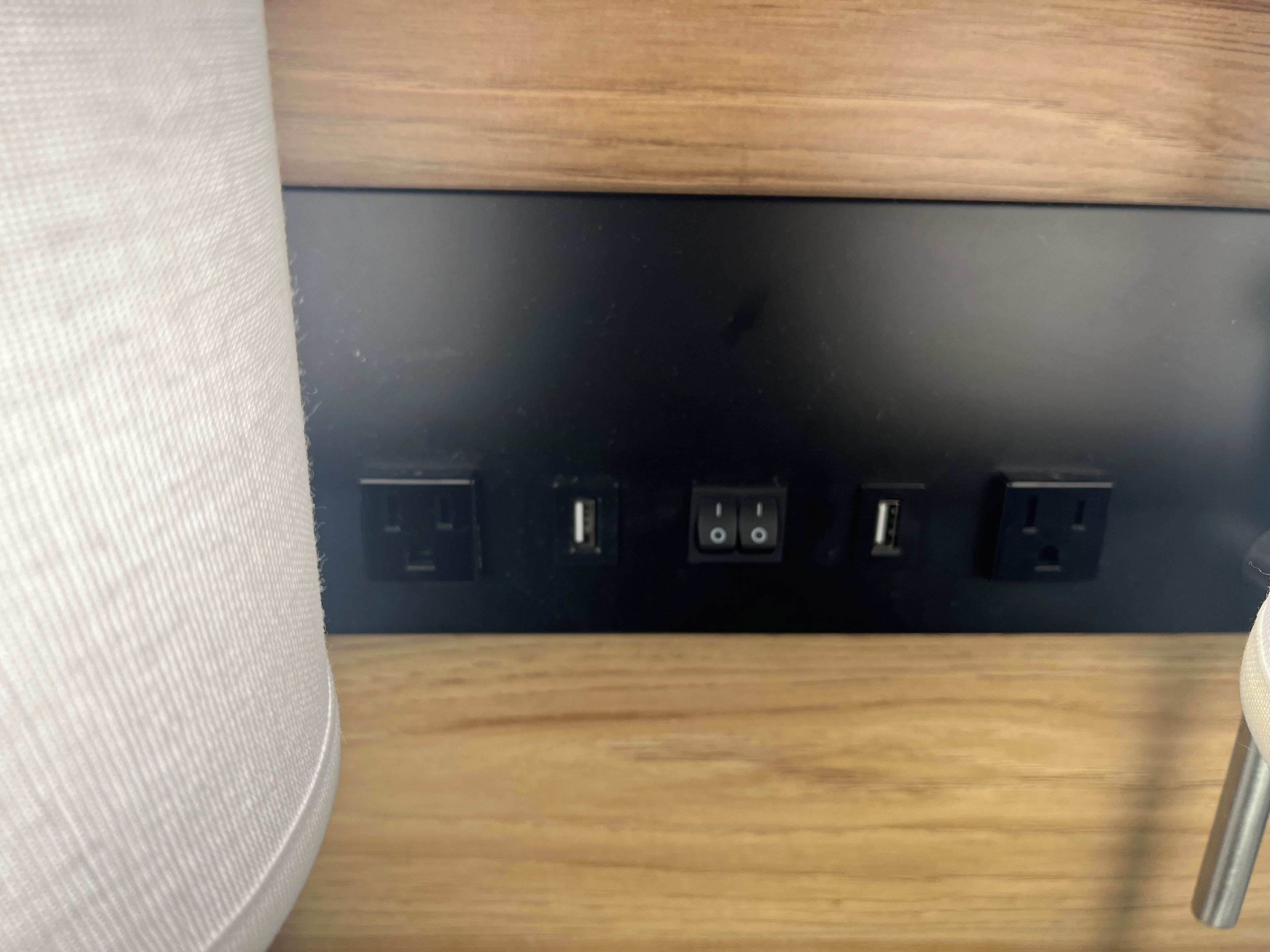 A black electrical panel with four sockets and two switches on a wooden surface.