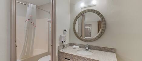 Un baño con ducha, inodoro, lavabo y espejo con marco decorativo.