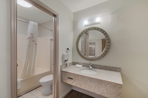 Un baño con ducha, inodoro, lavabo y espejo con marco decorativo.