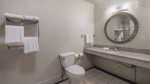 A standard hotel bathroom with a toilet, sink, mirror, towel rack, and toilet paper. - Red Roof Inn Crossville (Crossville)