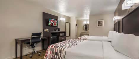Habitación de hotel con cama, escritorio, silla, televisión y refrigerador pequeño.