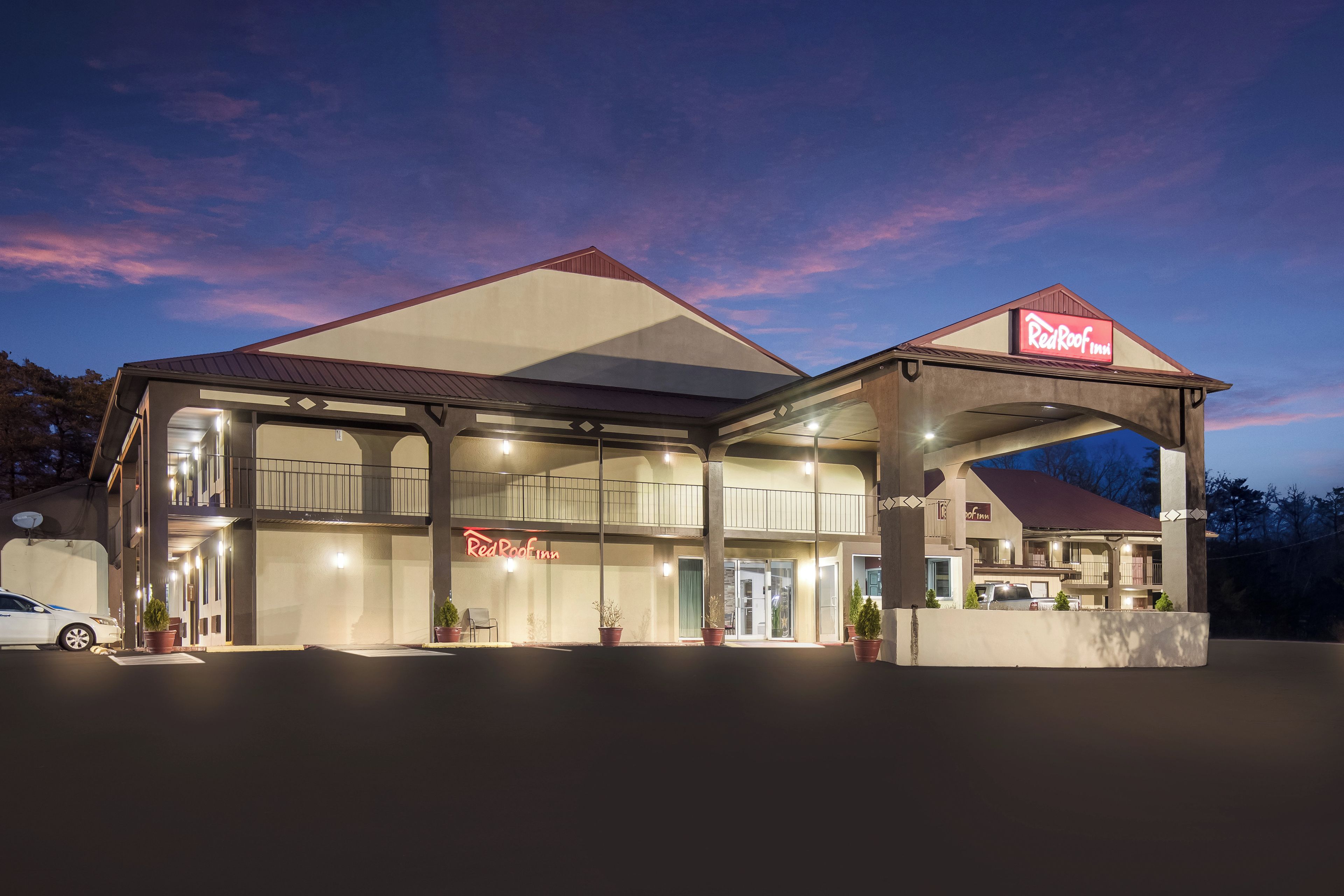 Un Red Roof Inn con una estructura de dos pisos, un área de estacionamiento techado y una antena parabólica en el techo.