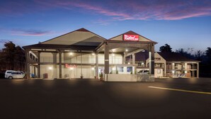 A Red Roof Inn with a two-story structure, a covered parking area, and a car parked in front. - Red Roof Inn Crossville (Crossville)
