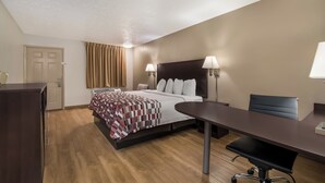 A hotel room with a bed, bedside lamps, a desk, and a chair. - Red Roof Inn Crossville (Crossville)