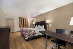 A hotel room with a bed, bedside lamps, a desk, and a chair. - Red Roof Inn Crossville (Crossville)