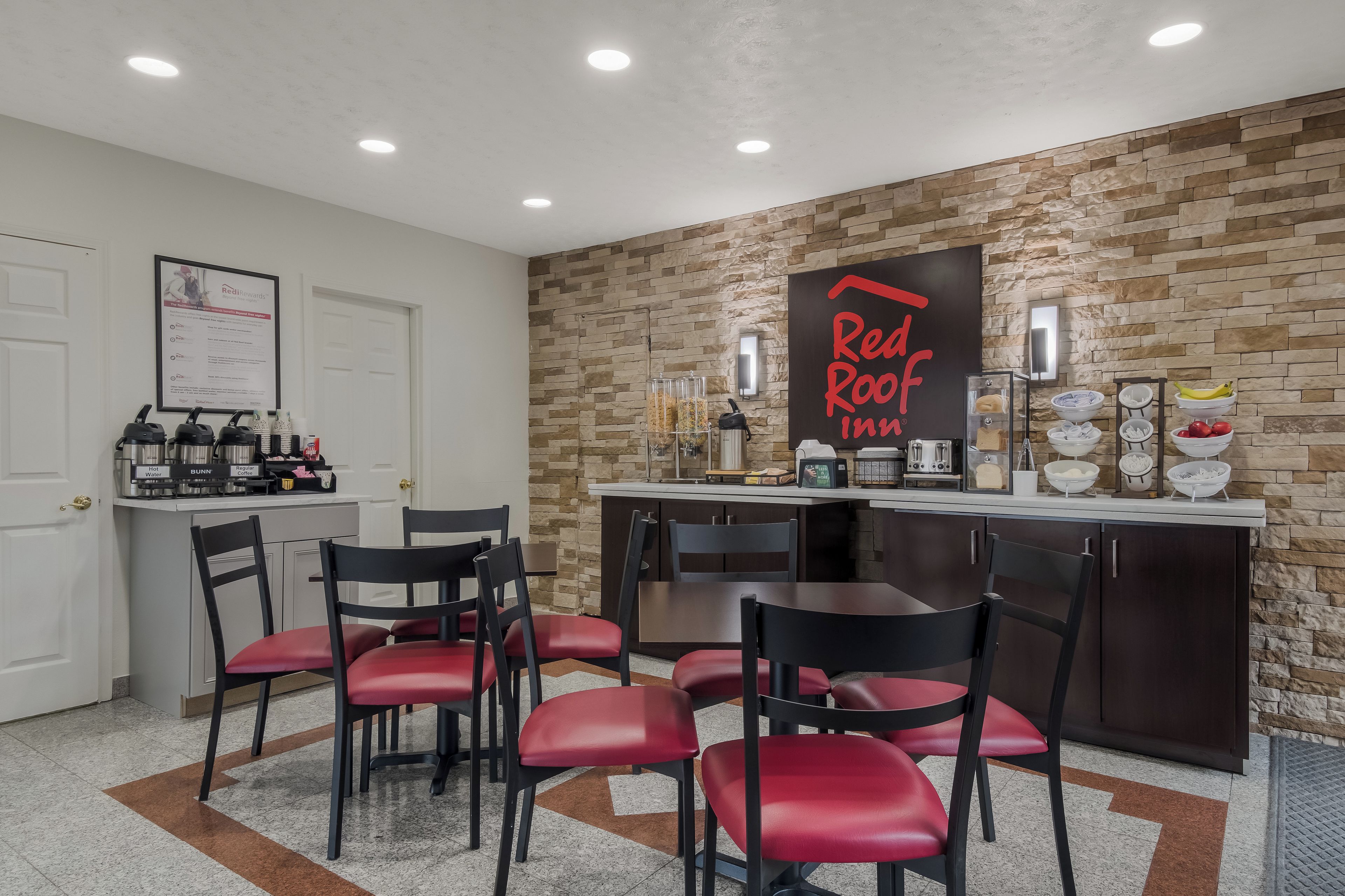 A Red Roof Inn kitchen with a stone wall backsplash, a coffee station, and a breakfast bar.