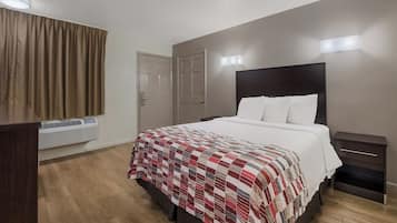A hotel room with a bed, bedside tables, a wardrobe, and a window with curtains.