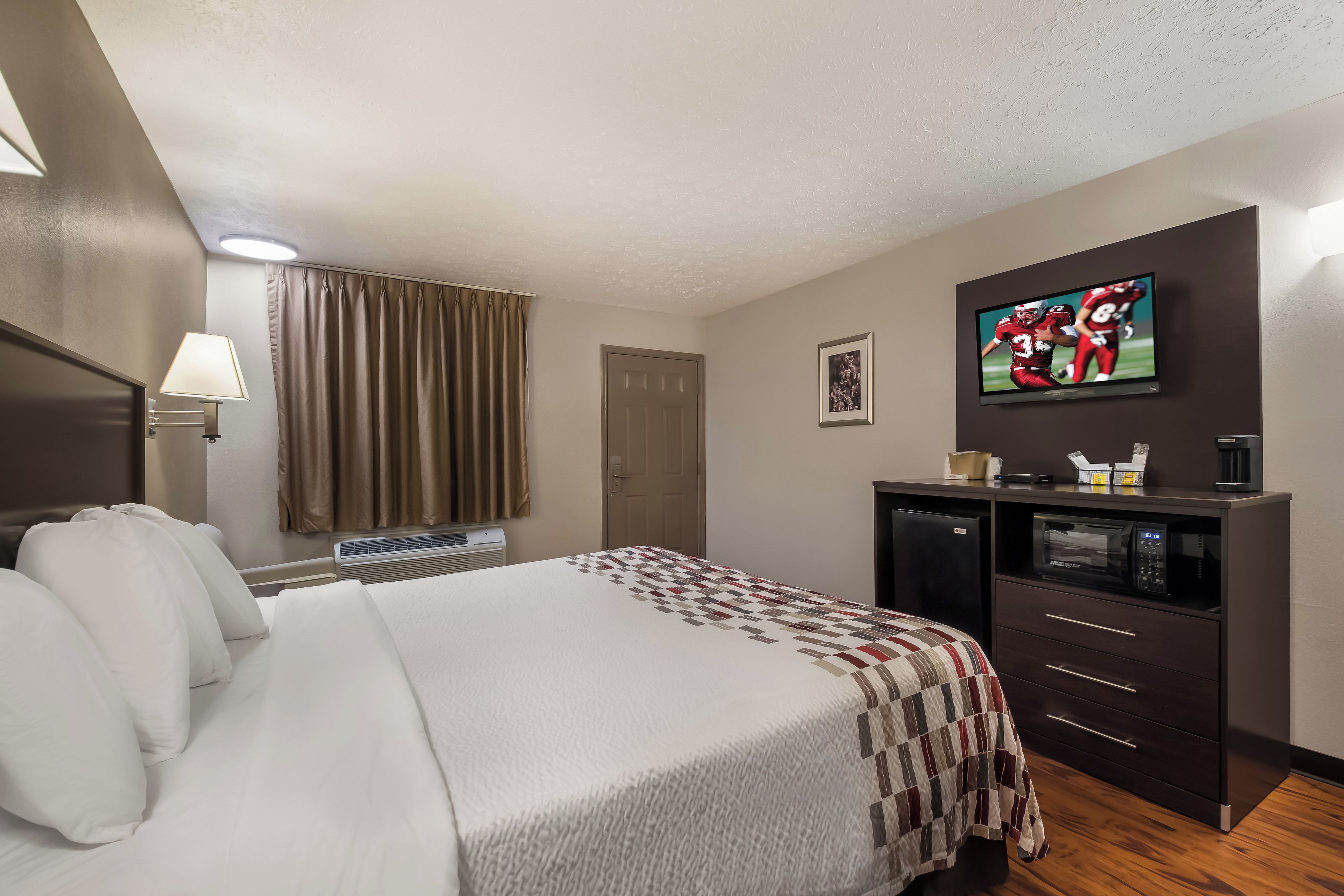 Une chambre d’hôtel équipée d’un lit, d’une télévision, d’un bureau avec une machine à café et d’un four à micro-ondes.