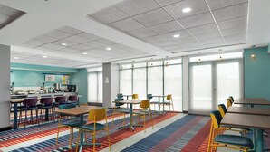 Een moderne hotelkamer met een keukenhoek, diverse zithoekjes en grote ramen die zorgen voor natuurlijk licht.