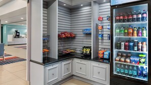 Een hoek van een winkel met een gekoeld schap vol drankjes en snacks.
