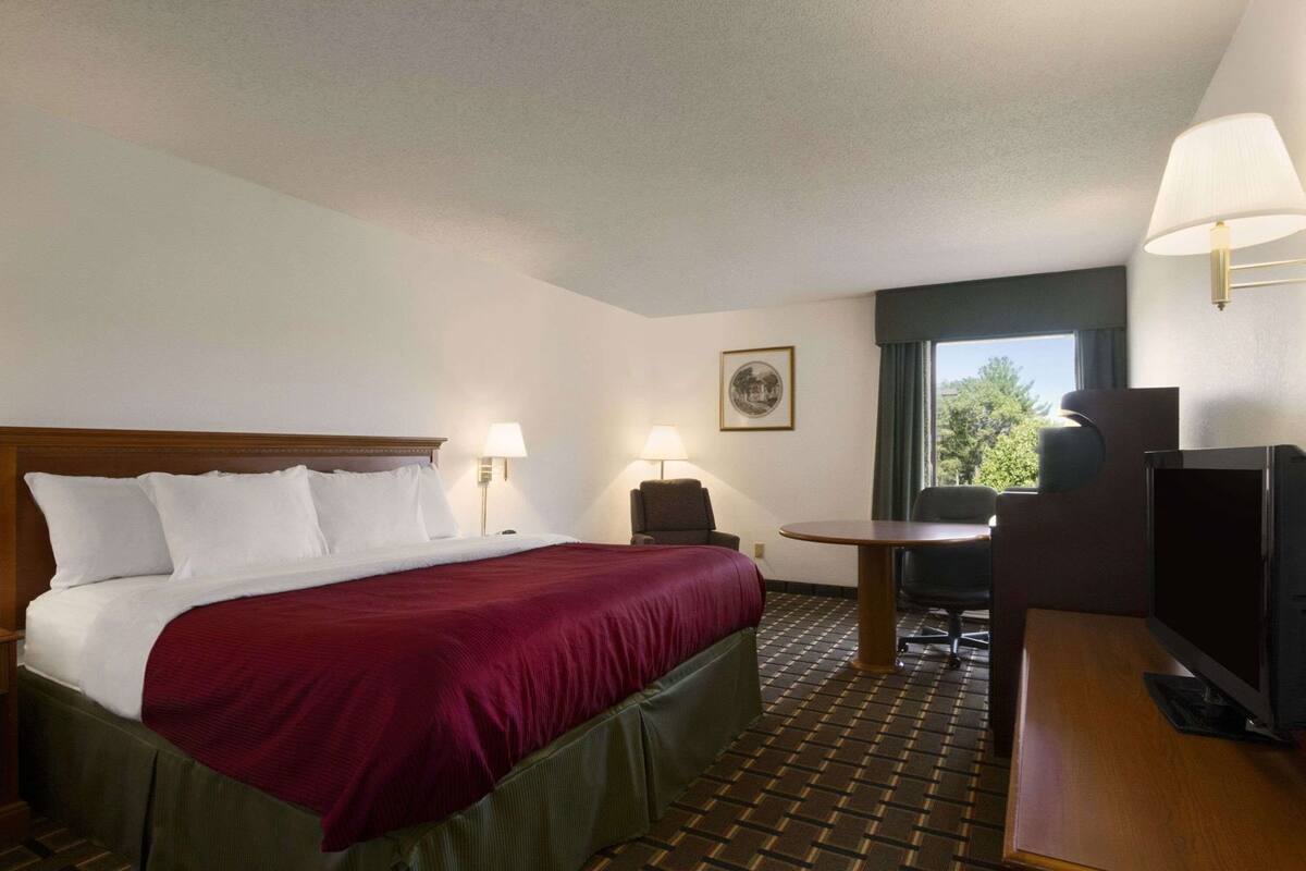 A hotel room with a bed, a desk, a chair, a television, and a window with a view.