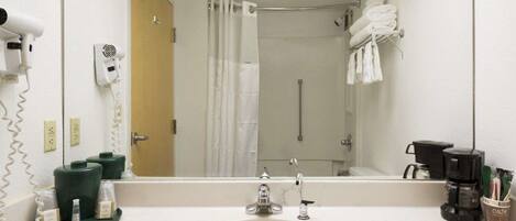 A hotel bathroom with a sink, mirror, hair dryer, and towel rack.