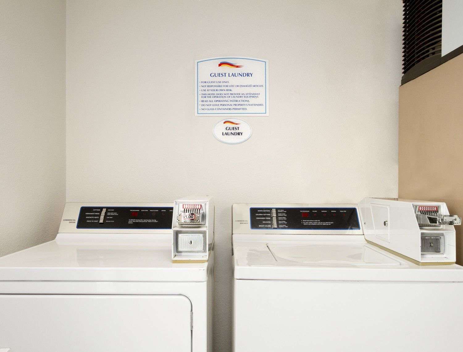 Un espace buanderie à la disposition des clients, équipé de deux machines à laver et surmonté d’une enseigne.