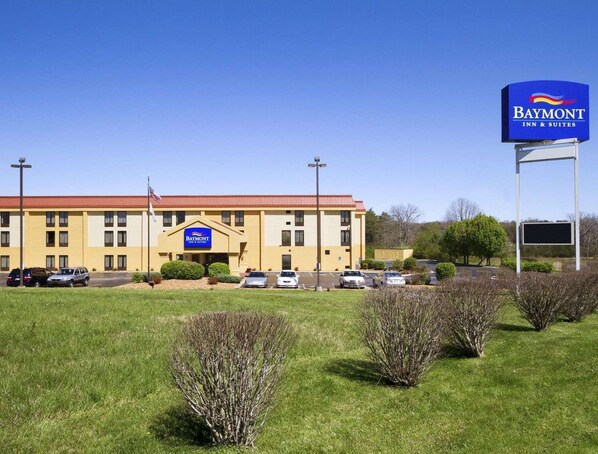 Stylish Baymont Inn & Suites features a central entrance and parking spaces amidst a well-manicured landscape.