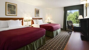 A hotel room with two beds, a desk, a chair, and a TV.