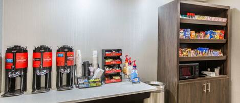 A self-service beverage station with coffee machines, a microwave, and a snack shelf.