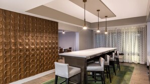 A modern dining area with a long table, multiple chairs, and pendant lighting.
