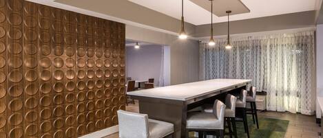Un comedor moderno con una mesa larga, varias sillas e iluminación colgante.
