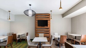 A modern dining area with wooden panel walls, a flat-screen TV, and contemporary furniture.