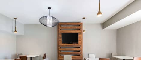 Un comedor moderno con paneles de madera, un televisor de pantalla plana y mobiliario contemporáneo.