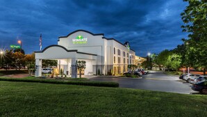 A Wingate by Wyndham hotel with a modern design, a covered entrance, and a parking lot.