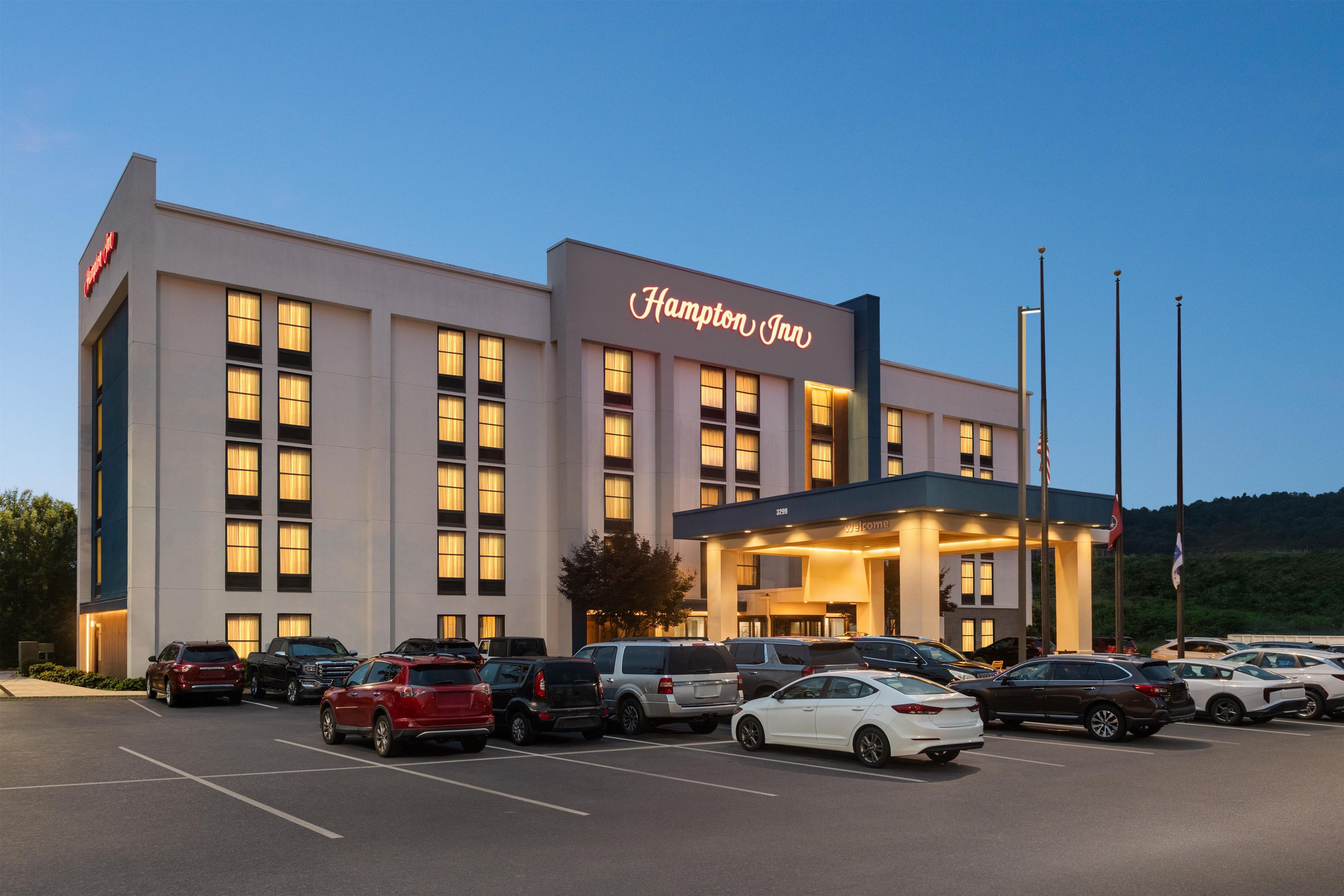 A Hampton Inn hotel with a parking lot full of cars.