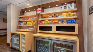 A snack display with various chips and a refrigerated beverage cooler. - Hampton Inn Bristol (Bristol)