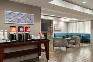 A hotel lobby with a coffee station, seating area, and a fireplace. - Hampton Inn Bristol (Bristol)