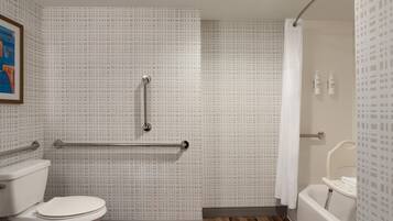 A bathroom with a toilet, a shower with a grab bar, and a bathtub.