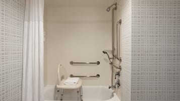 Un baño con bañera, ducha e inodoro. Cuenta con barras de apoyo para mayor seguridad.