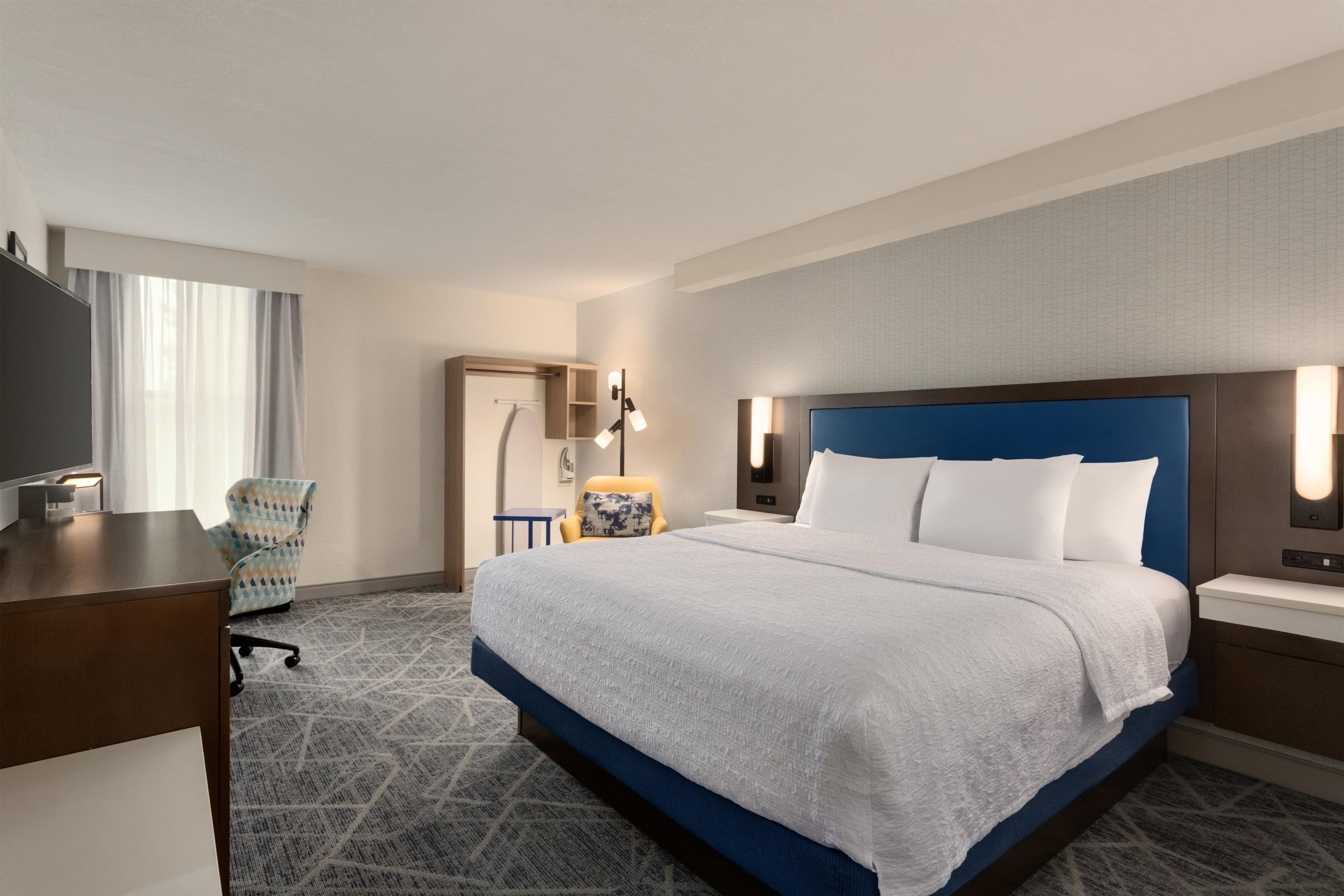 Una habitación de hotel con una cama grande, un escritorio, una silla y un televisor.